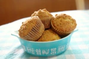 banana crumb muffins in a turquoise vintage Pyrex bowl on a table with an aqua table cloth