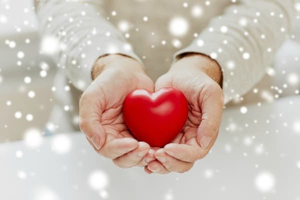 love, charity and people concept - close up of senior man with red heart in hands over snow
