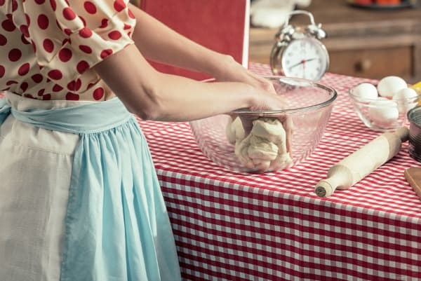 cropped shot of housewife preparing dough in glass bowl at kitchen