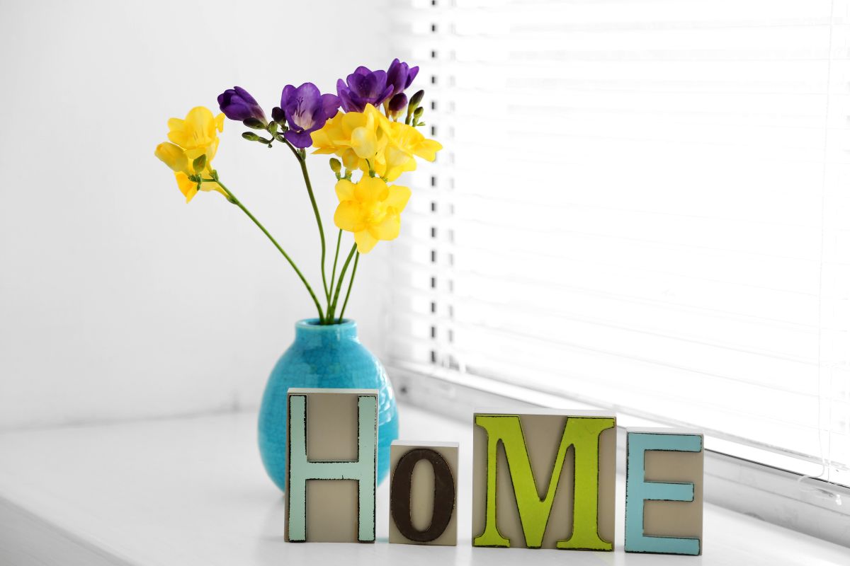 blue vase with flowers and blocks in front of it spelling out home