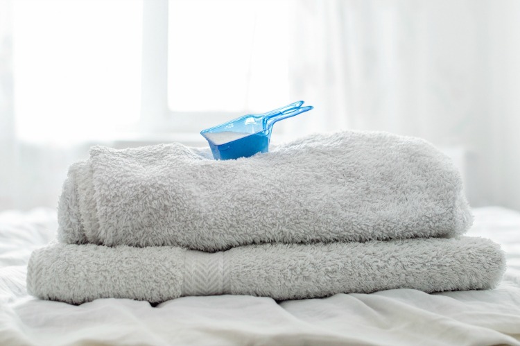 towels folded with laundry soap scoop on top