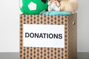 Donation box with toys on table against light background
