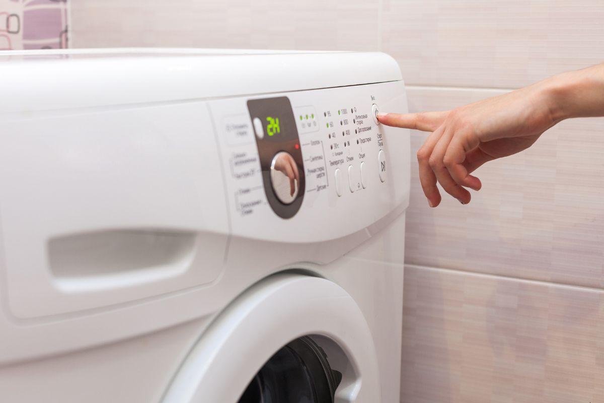 person pushing the start button on a washer