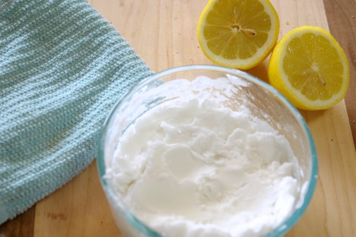 cleaning scrub, cloth, and lemon on table