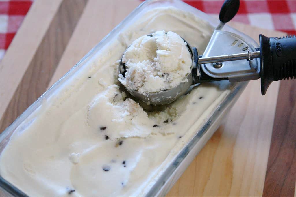 chocolate chip cookie dough ice cream in glass container with scoop on top