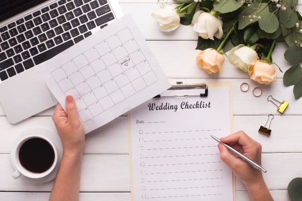 desk with laptop, cup of coffee, roses, and wedding checklist