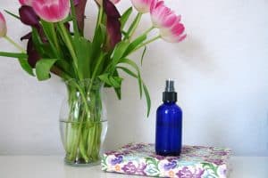 blue spray bottle on floral journal next to fresh flowers