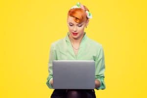 retro housewife with red hair, looking at a laptop
