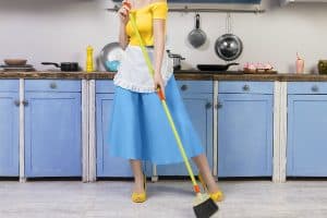 woman wearing a '50s style dress, heels, and holding a broom