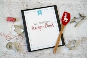 Christmas Recipe Book on white table with cookie cutters and spatula