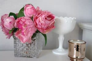 pink peonies in glass vase with milk glass and rose gold candle