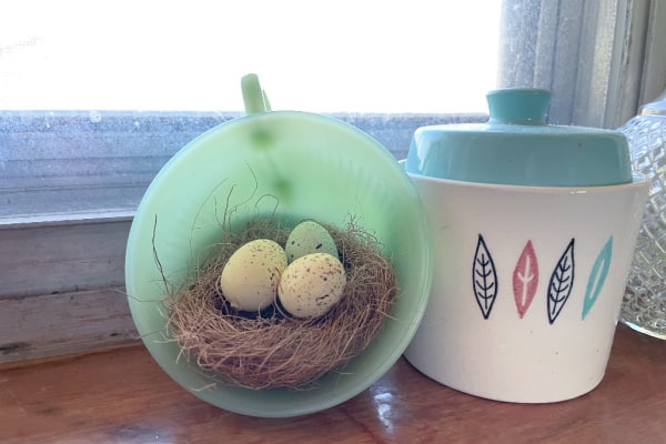 Jadeite vintage teacup with bird nest and eggs sitting on window sill