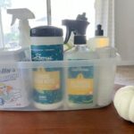 cleaning supplies in plastic caddy on table with white pumpkin