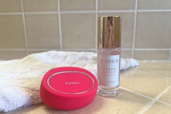 pink FOREO BEAR on bathroom countertop with pink and white hand towel and serum