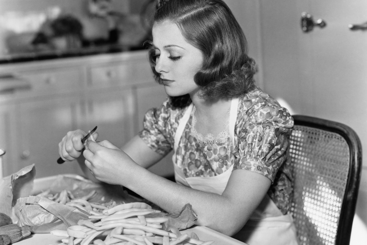 1940s housewife trimming green beans at kitchen table