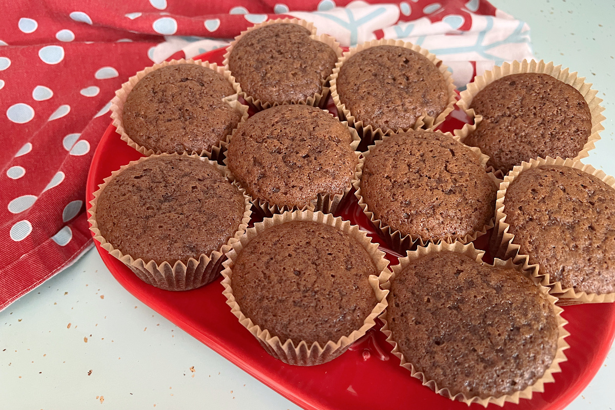 gingerbread muffins on red plate sitting on aqua counter with a red and blue snowflake dish towel