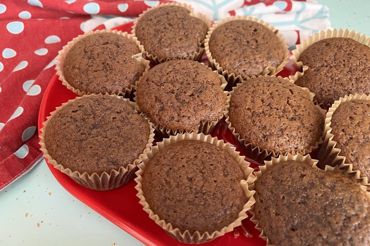 gingerbread muffins on red plate sitting on aqua counter with a red and blue snowflake dish towel